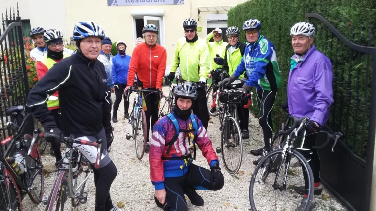 Groupe de cyclos du club devant un portail, vélos à la main